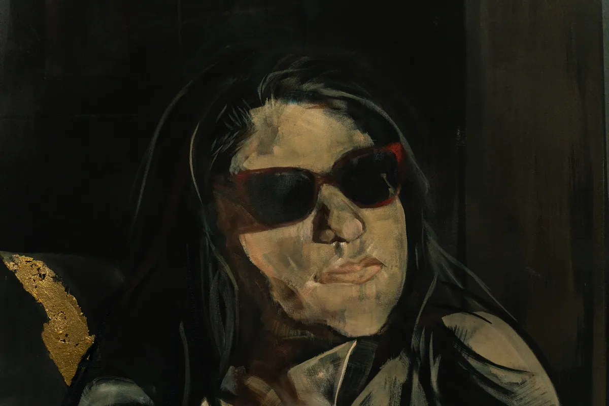 Detail of the face and sunglasses emerging from the dark ground